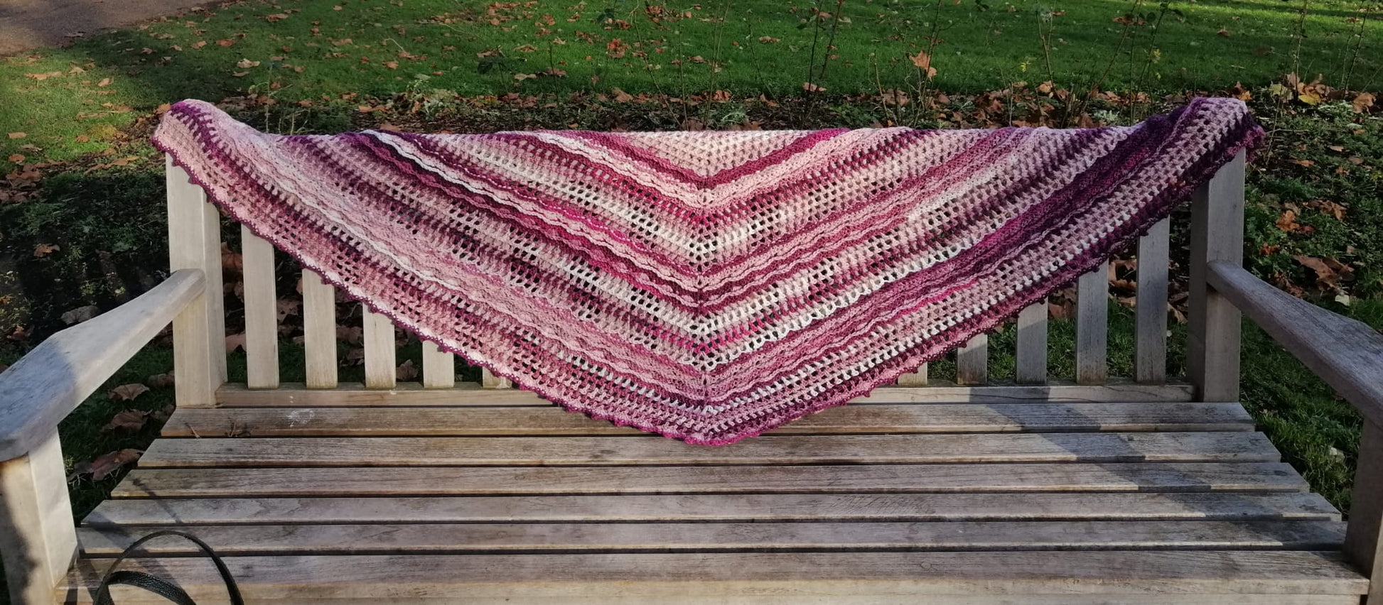 Showing it's full length and width, you can also see the pattern of whites, pinks and mauves used in this design of 'Antique Rose Crochet Shawl'.