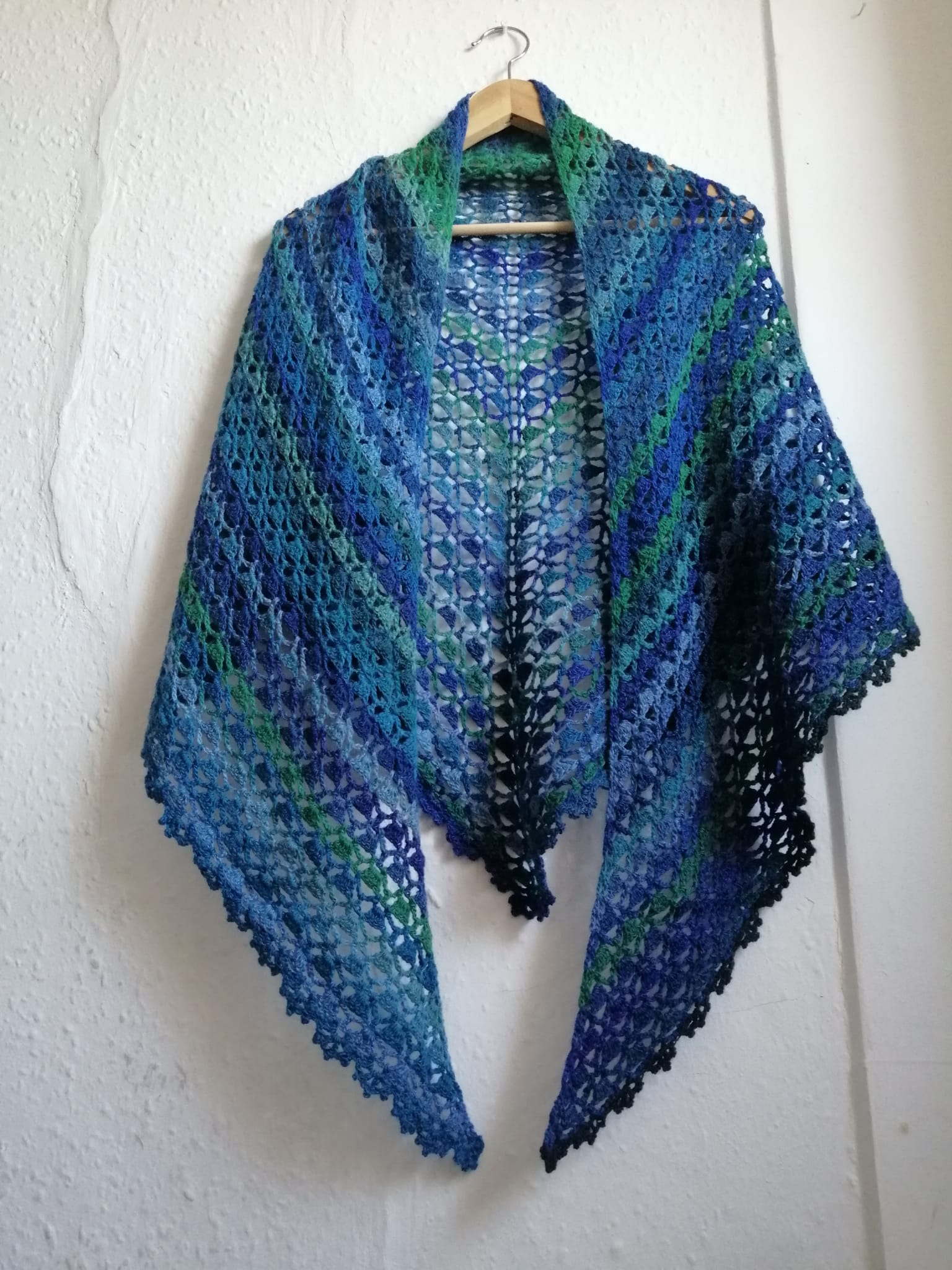 A unique, handcrafted, lacy shawl called 'Blue Geode Crochet Shawl' in blues and greens. This shawl is available for delivery in the UK.