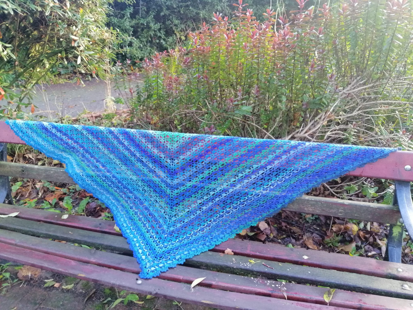 An image of our 'Blue Geode Crochet Shawl' where you can the full lace pattern and the various shades of blues and greens.