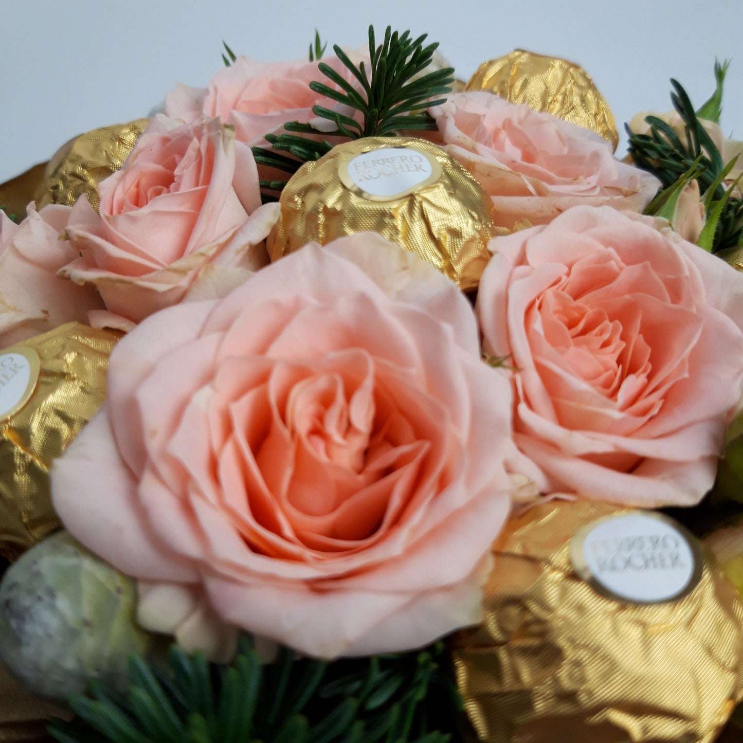 An image of our 'Christmas Sweet Treat Hatbox', seen is a close-up of the pale pink roses used, as well as the tasty Ferrero Rocher chocolates, Brunia, and Pine.