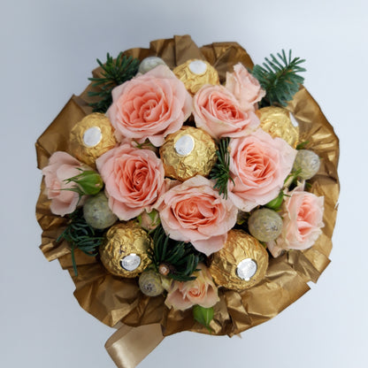 A picture where you can see the top of our 'Christmas Sweet Treat Hatbox', surrounded by golden tissue paper are pale pink Roses, luxury Ferrero Rocher chocolates, Pine and Brunia berries.