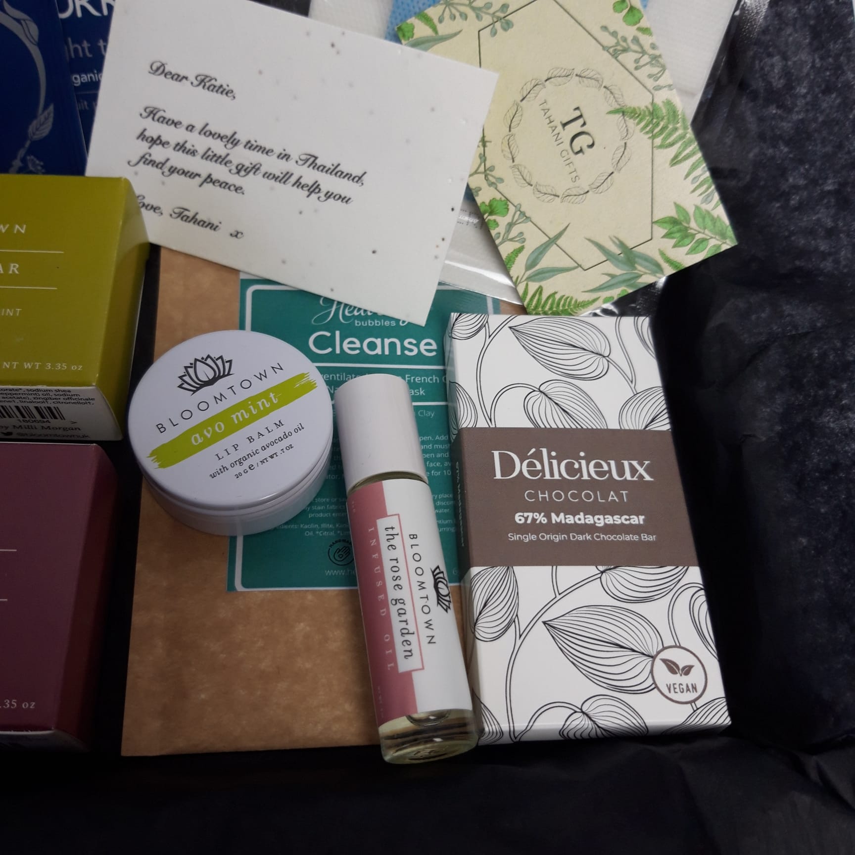 Close-up of our essential 'First-Class Wanderlust' letterbox gift showcasing our organic chocolate, lip balm, face mask and roll on infuse.