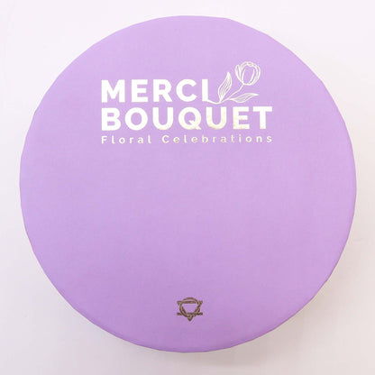 A lilac, round hat box lid with Merci Bouquet Floral Celebrations in white. This soap hatbox is a thoughtful gift for birthdays and at home spa days.