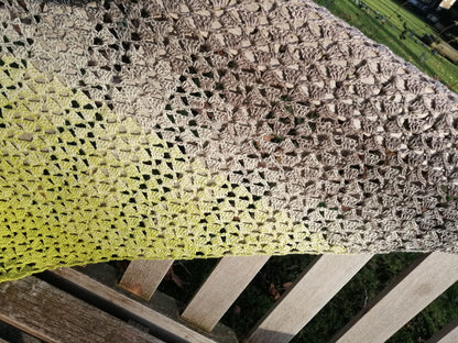 Close-up photo of our 'Mossy Stone Crochet Shawl' where you can see the pattern and colour change from green to brown to beige.