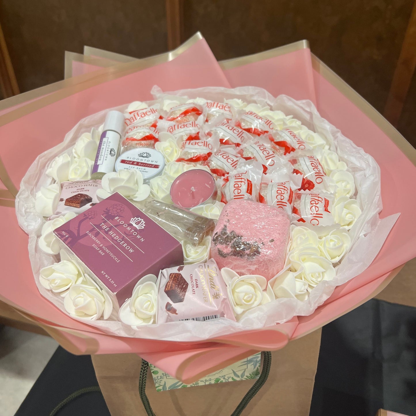 'Serene Delights' is a gift bouquet of white, lasting roses, delicious chocolates, and luxury spa treats including a shower steamer, bath salts, lip balm and more.